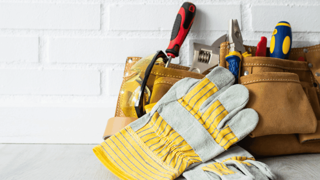 Tool belt filled with essential DIY remodeling tools leaning against a tiled wall
